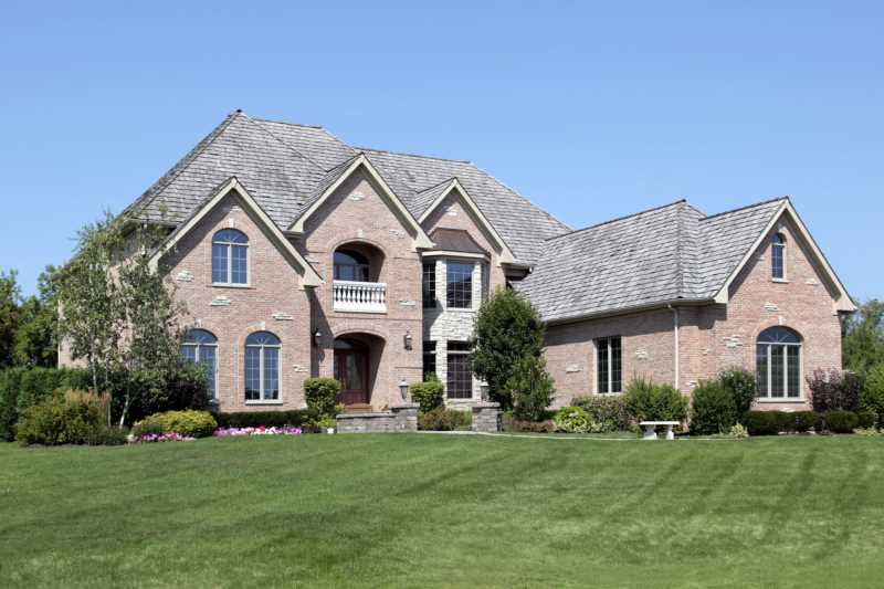 Large brick home with arched entry and front balcony